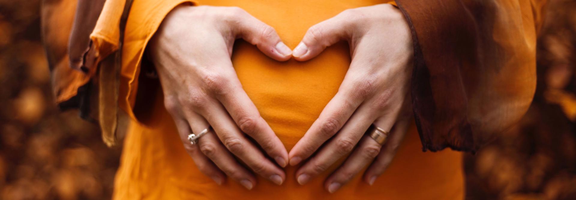 Bauch einer Schwangeren mit Händen davor